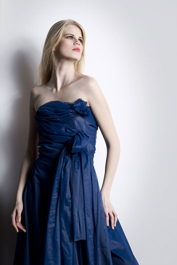 An elegant woman is photographed in a flowing blue dress 
